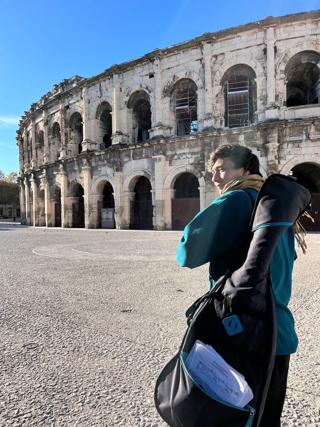 Lisandro con la guitarra al hombro frente a un anfiteatro romano.